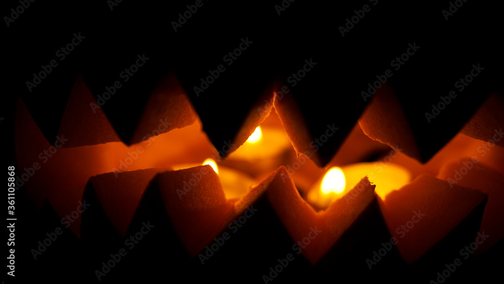Halloween pumpkin with candles glowing inside at black background
Halloween pumpkin with candles glowing inside at black background