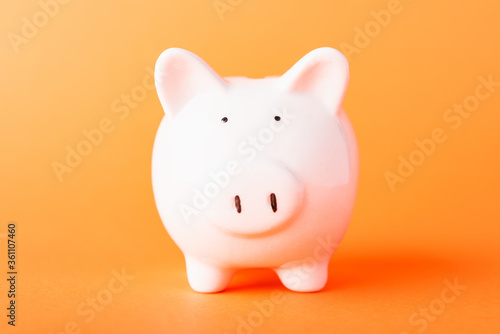 Front small white fat piggy bank, studio shot isolated on orange background and copy space for use, Finance, deposit saving money concept