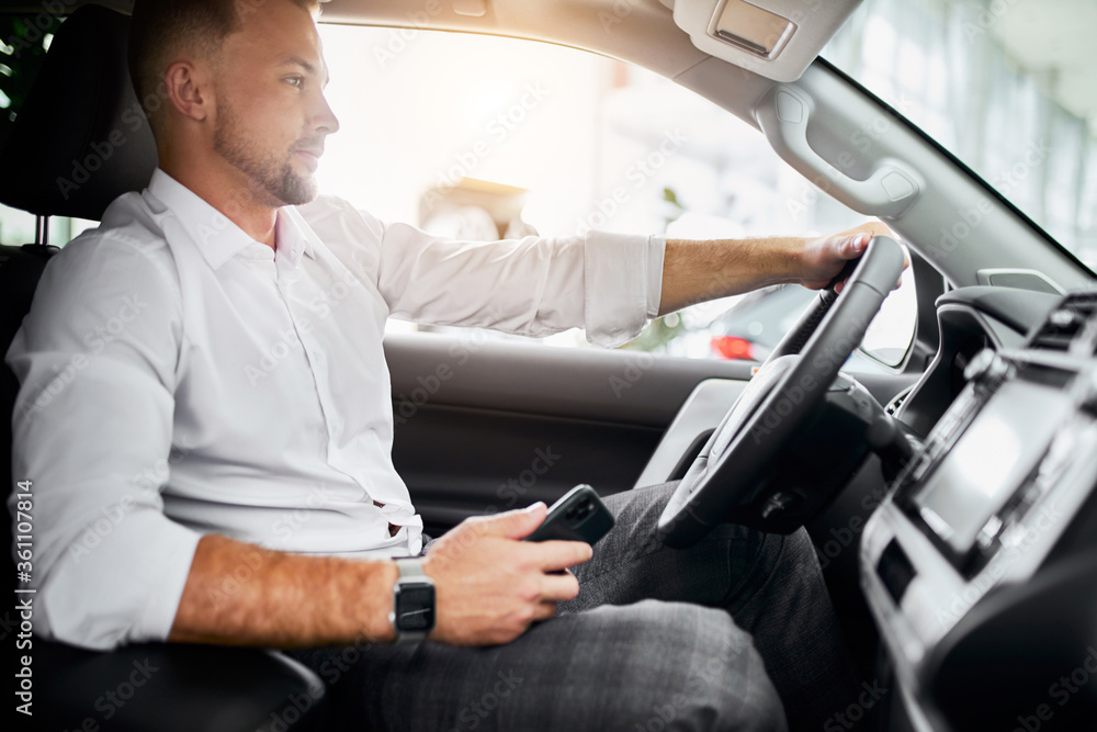 young caucasian handsome business man test drive new car. guy is examining new car's design and interior in car dealership young caucasian handsome business man test drive new car. guy is examining new car's design and interior in car dealership