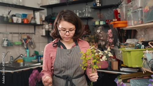 female making bouquet from summer wild flowers close up. woman at shop workshop. florist at work preparing floral composition front view. natural ecologic lifestyle.