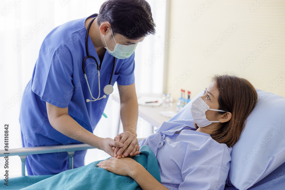 Asian male doctors wear uniforms and medical masks, holding hands with middle-aged female patients to encourage patients. Asian male doctors wear uniforms and medical masks, holding hands with middle-aged female patients to encourage patients.