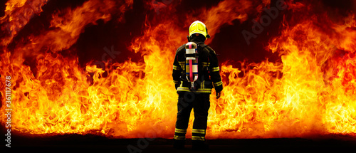 Photo Rear of firefighter with fire uniform and equipment on flame background with cop