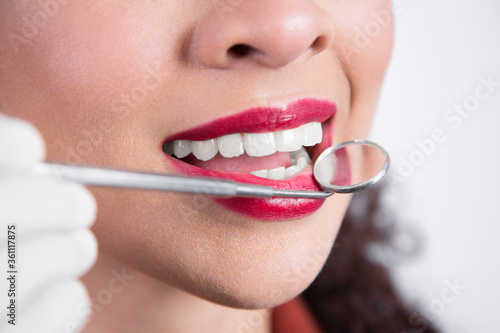 close up of a young woman having her teeth checked, dentist with small mirror