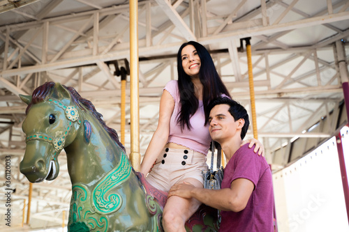 Couples play carousel while visiting an amusement park.