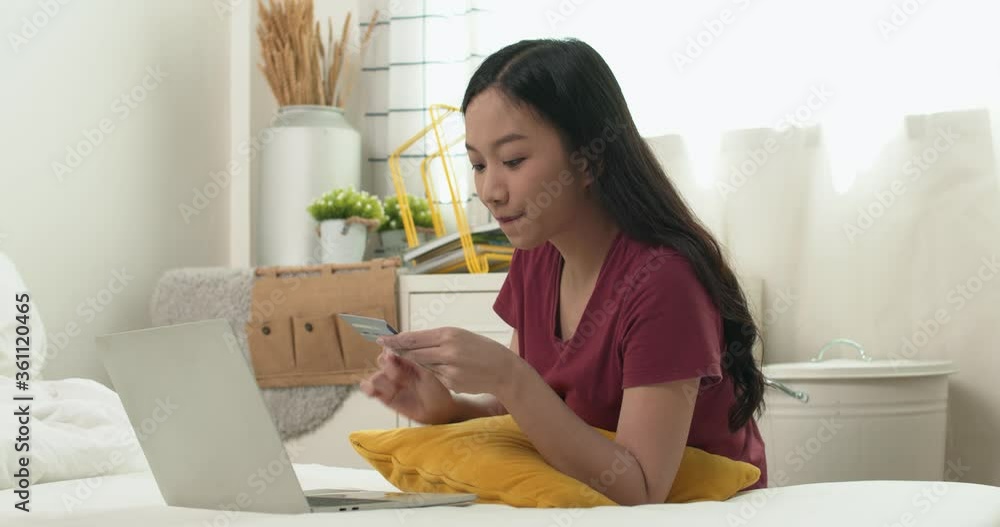 woman use laptop to shopping online on bed at home, looking favorite product and pay by credit card