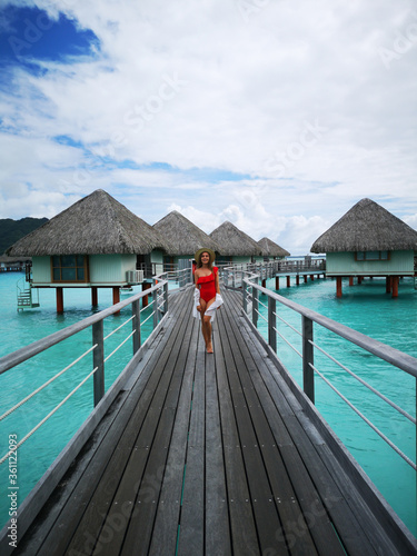 Fototapeta Naklejka Na Ścianę i Meble -  beautiful girl in swimsuit posing on dock, tropical resort in background