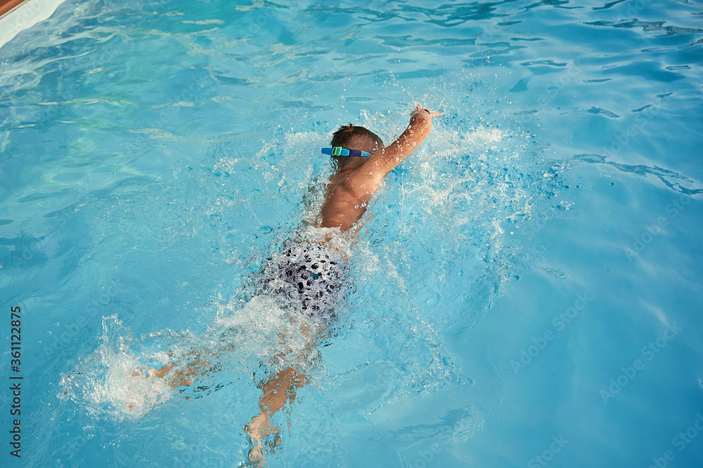 Boy swimming in the open pool in summer