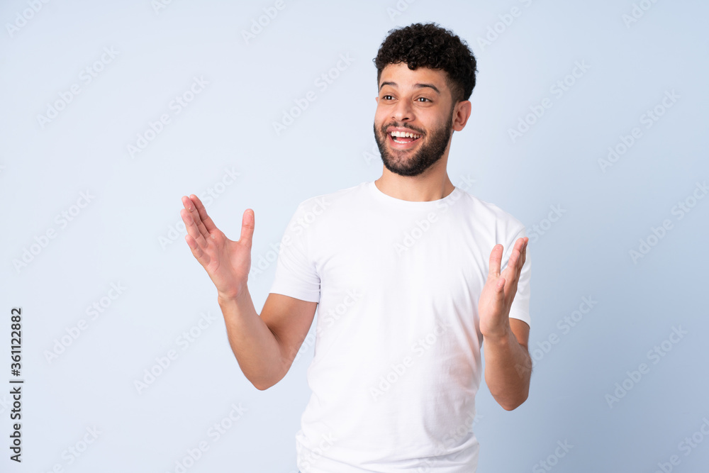 Young Moroccan man isolated on blue background with surprise facial expression Young Moroccan man isolated on blue background with surprise facial expression