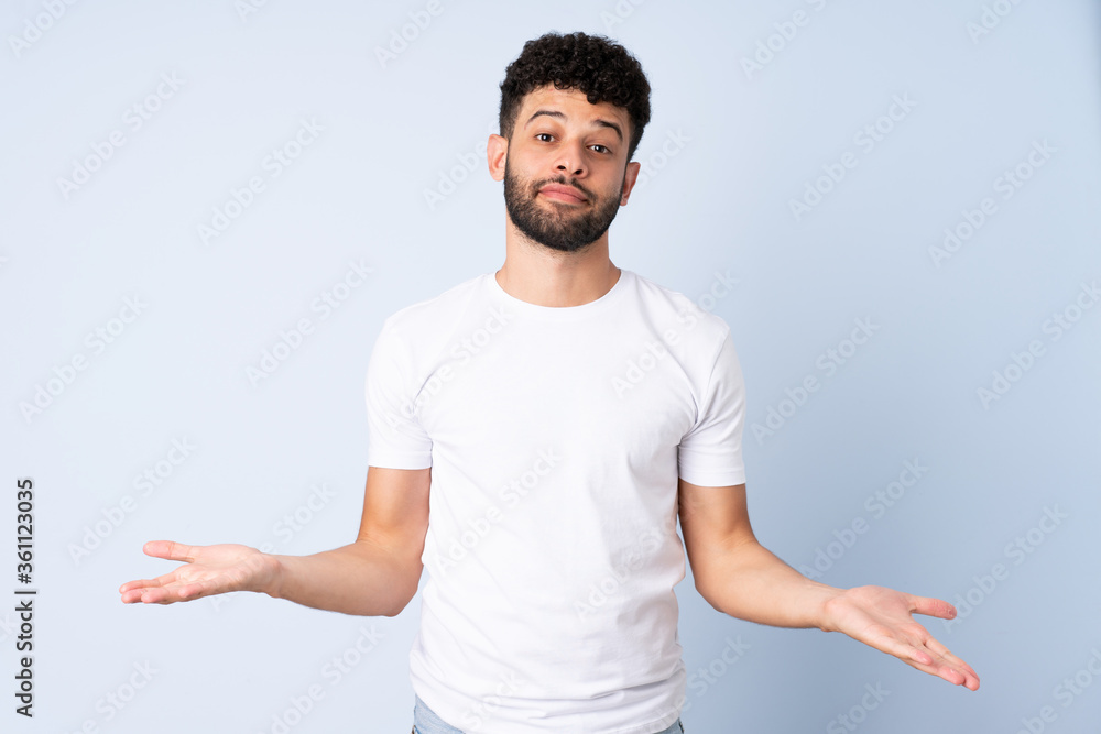 Young Moroccan man isolated on blue background having doubts Young Moroccan man isolated on blue background having doubts