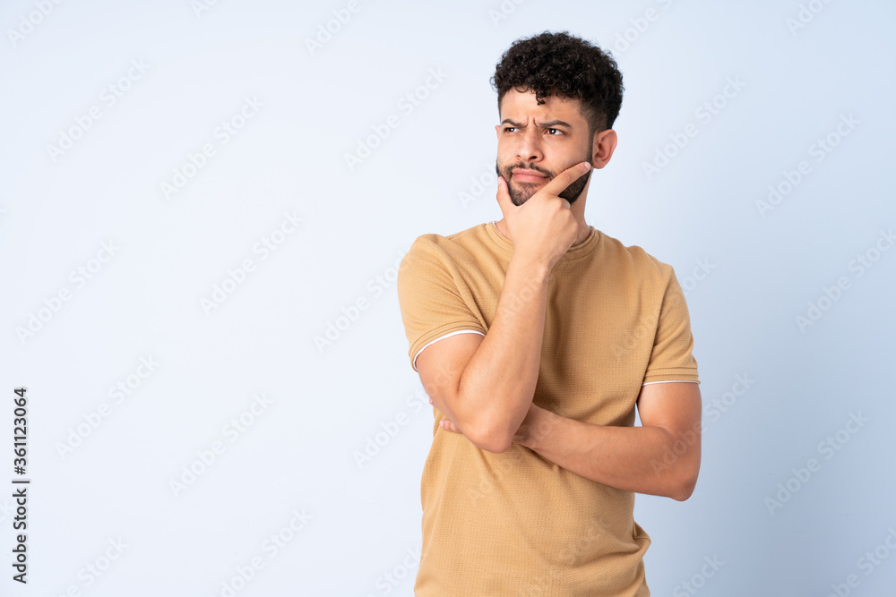 Young Moroccan man isolated on blue background having doubts Young Moroccan man isolated on blue background having doubts