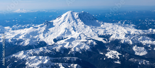 Aerial View of Idaho mountains from the sky while inside an airplane. View of brown mountains and trees covered with snow
