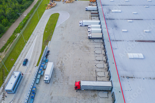 Aerial view of goods warehouse. Logistics center in industrial city zone from above. Aerial view of trucks loading at logistic center