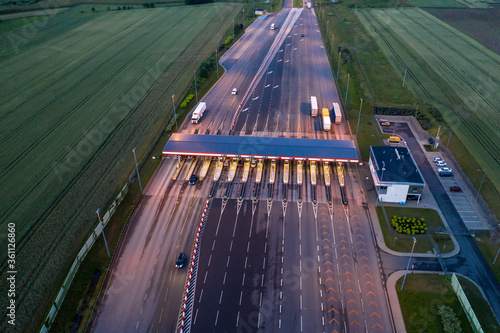 Car traffic transportation on multiple lanes highway road and toll collection gate, drone aerial top view at Night. Commuter transport, city life concept.A2 Poland Lodz