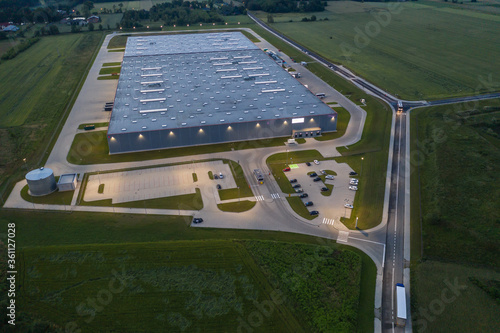 Aerial top down view of the large logistics park with warehouse at Night, loading hub with semi trucks with cargo trailers standing at the ramps for load/unload goods