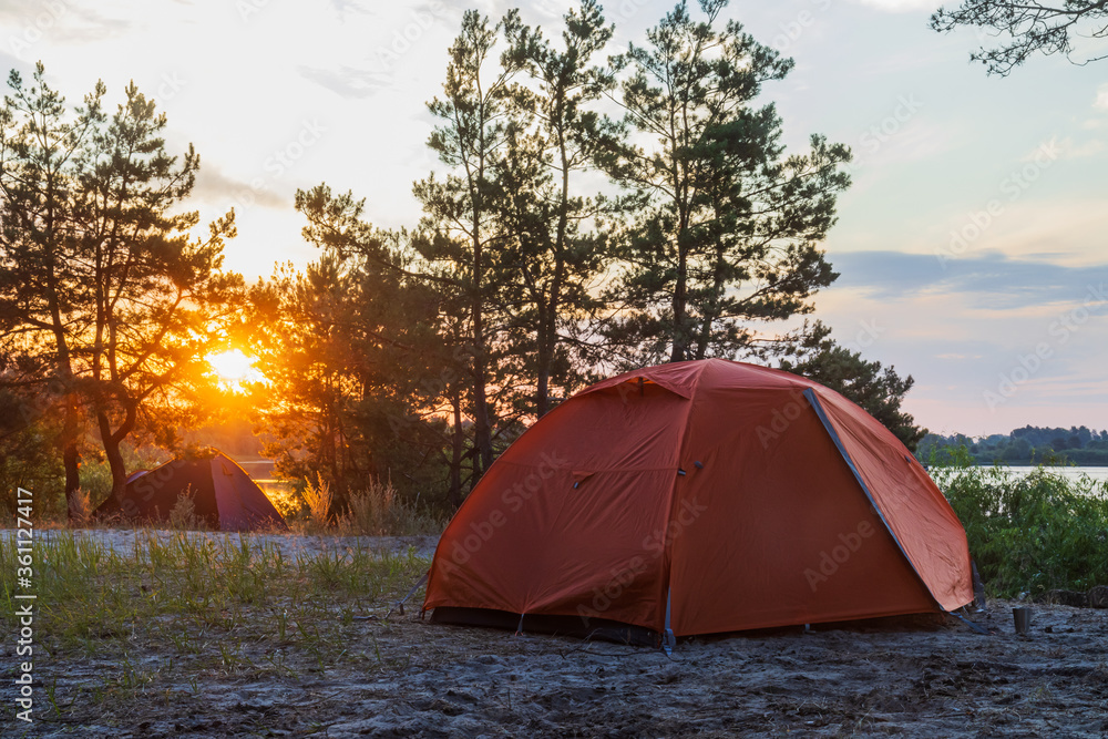 tents stand at sunrise on the river bank