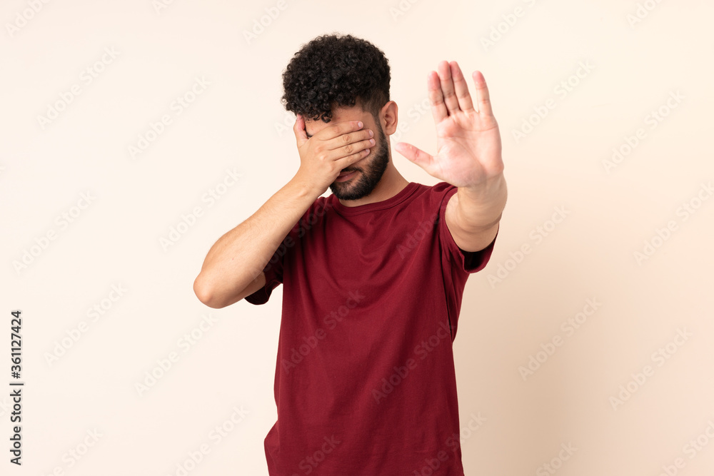 Young Moroccan man isolated on beige background making stop gesture and covering face Young Moroccan man isolated on beige background making stop gesture and covering face