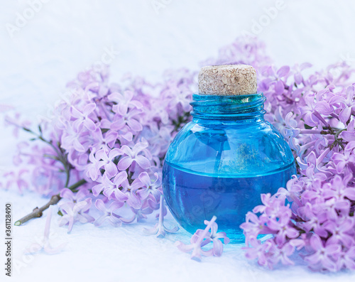 Glass bottle with aromatic oil and lilac flowers for Spa and aromatherapy. Selective focus