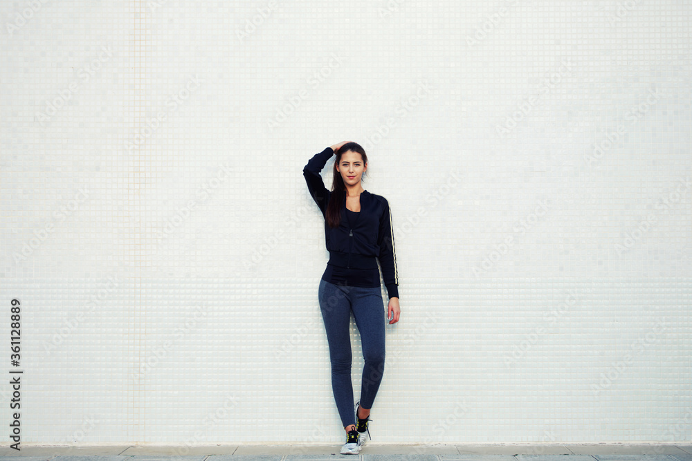 Full length portrait of an attractive and sporty young woman standing against a white background while getting ready for workout outdoors, cross process, filtered image Full length portrait of an attractive and sporty young woman standing against a white background while getting ready for workout outdoors, cross process, filtered image