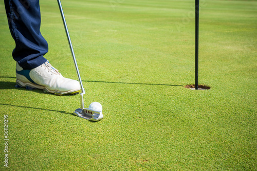 golfeur avec putter devant le trou