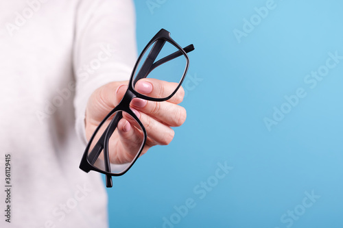 Glasses in a hand on a blue background.