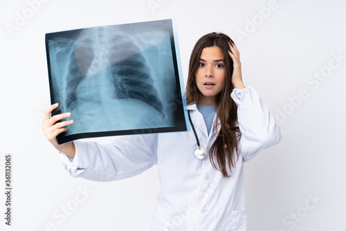 Teenager girl over isolated white background wearing a doctor gown and holding a bone scan