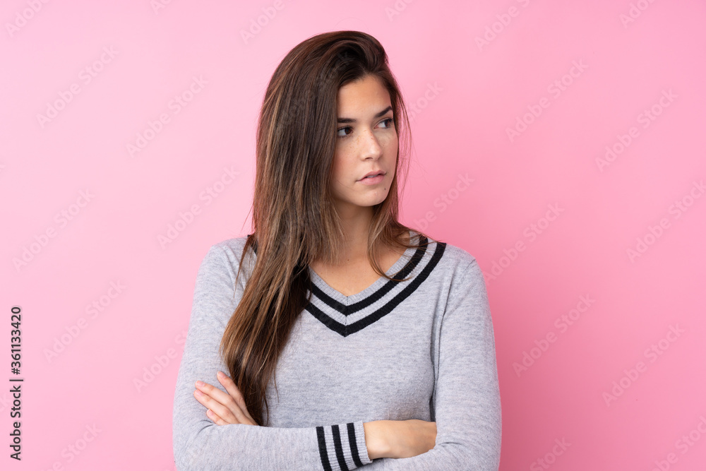Fototapeta premium Teenager girl over isolated pink background looking side