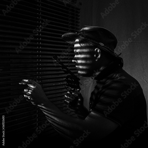 man looking through blinds with gun © Gary
