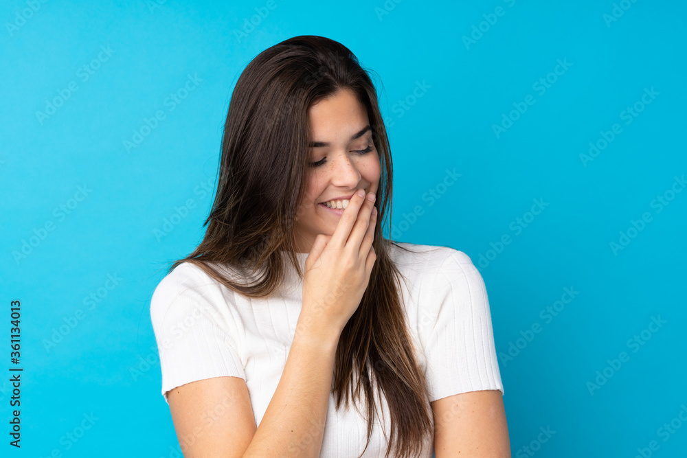 Teenager girl over isolated blue background smiling a lot Teenager girl over isolated blue background smiling a lot