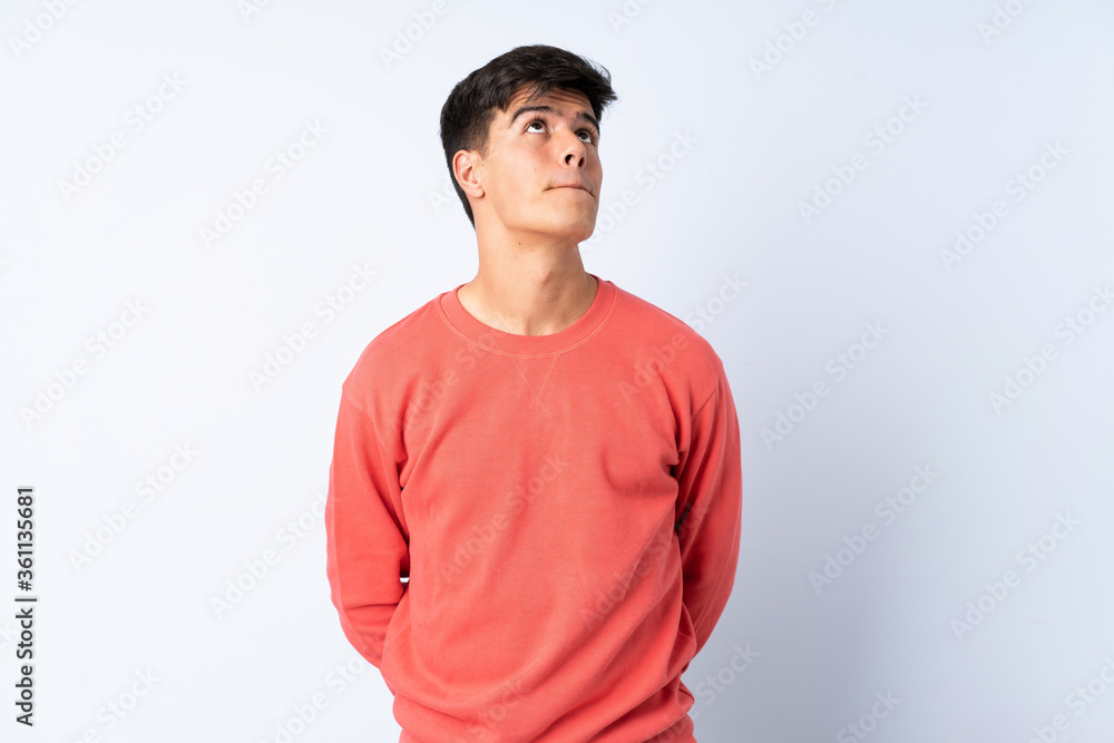 Handsome man over isolated blue background and looking up Handsome man over isolated blue background and looking up