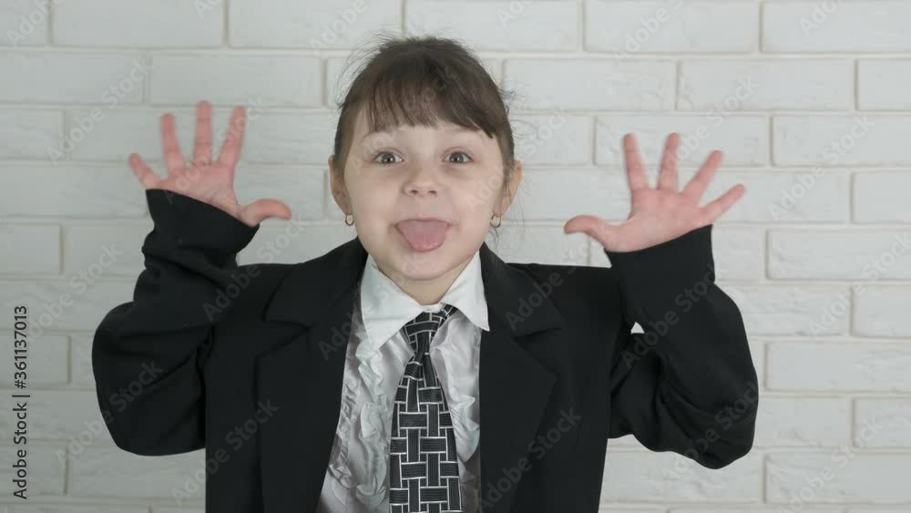 Young business child. Cheerful little girl in a business suit shows her tongue. Young business child. Cheerful little girl in a business suit shows her tongue.