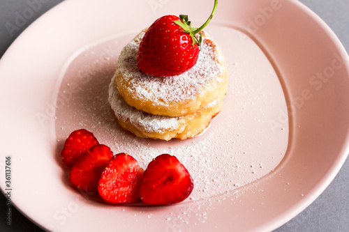 Frying homemade Cottage cheese pancakes Russian syrniki with strawberry on plate. Breakfast time photo