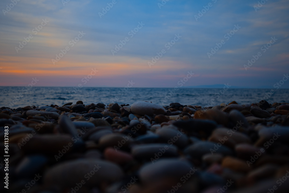 colorful yellow pink sunset on rocky beach with cloudy sky colorful yellow pink sunset on rocky beach with cloudy sky