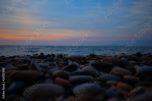 colorful yellow pink sunset on rocky beach with cloudy sky