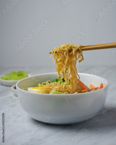Ramen noodles soup in white bowl and chopsticks to pick up noodles  copy space