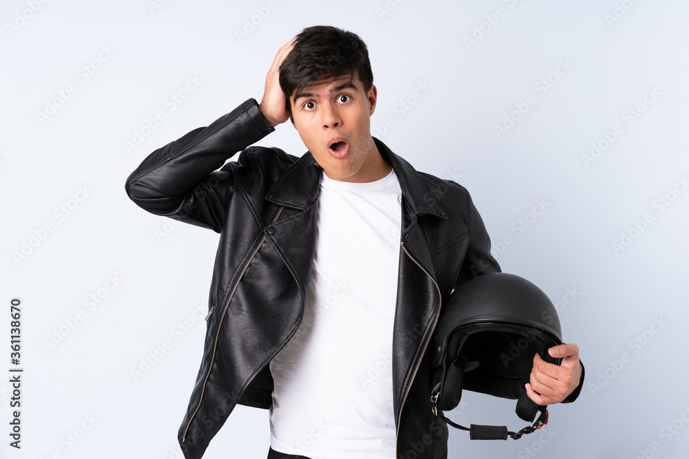 Man with a motorcycle helmet over isolated blue background with surprise facial expression Man with a motorcycle helmet over isolated blue background with surprise facial expression