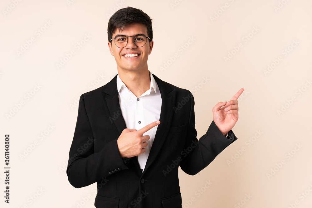 Businessman over isolated beige background pointing finger to the side Businessman over isolated beige background pointing finger to the side