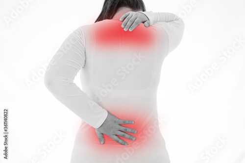 Black and white shot of woman feeling exhausted and suffering from neck and back pain and injury on isolated white background with red spot. Health care and medical concept.
