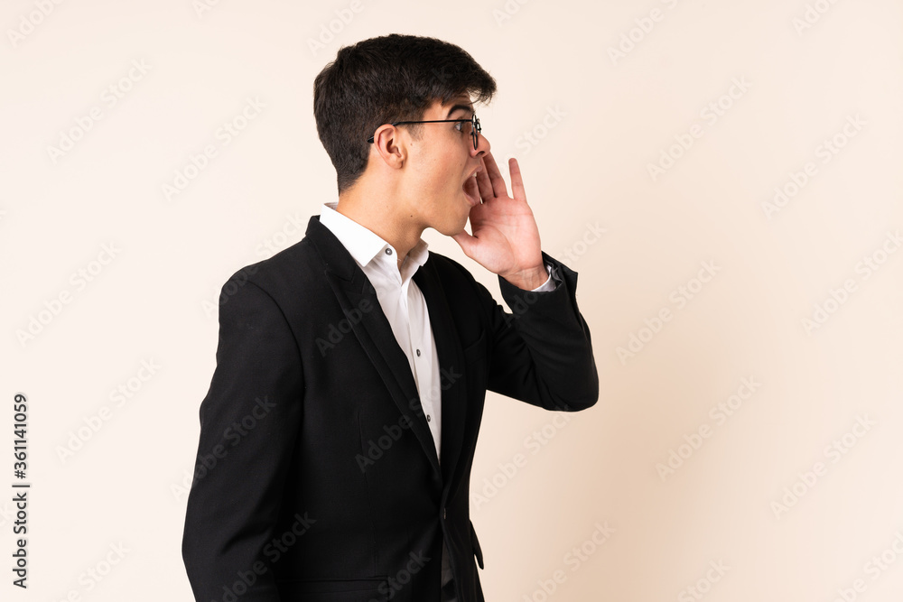 Businessman over isolated beige background shouting with mouth wide open Businessman over isolated beige background shouting with mouth wide open