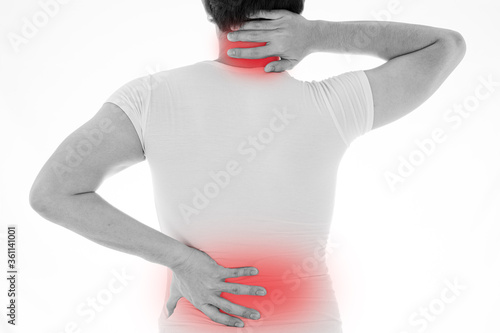 Black and white shot of man feeling exhausted and suffering from neck and back pain and injury on isolated white background with red spot. Health care and medical concept.