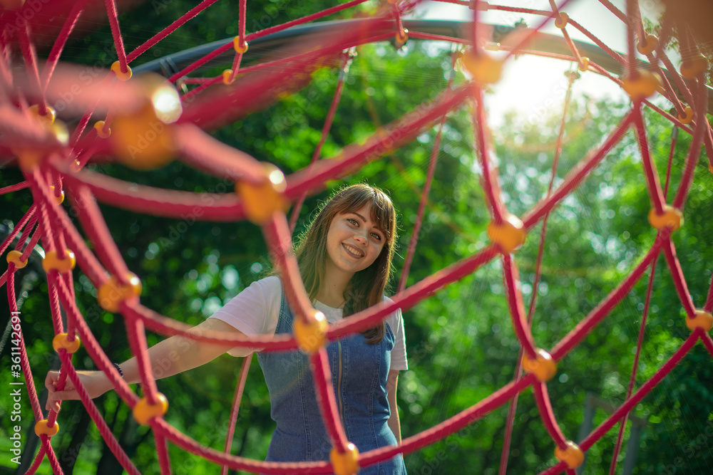 cheerful girl portrait smile Caucasian white person photography posing and looking at camera in summer day time park outdoor environment space foreshortening through grid foreground frame