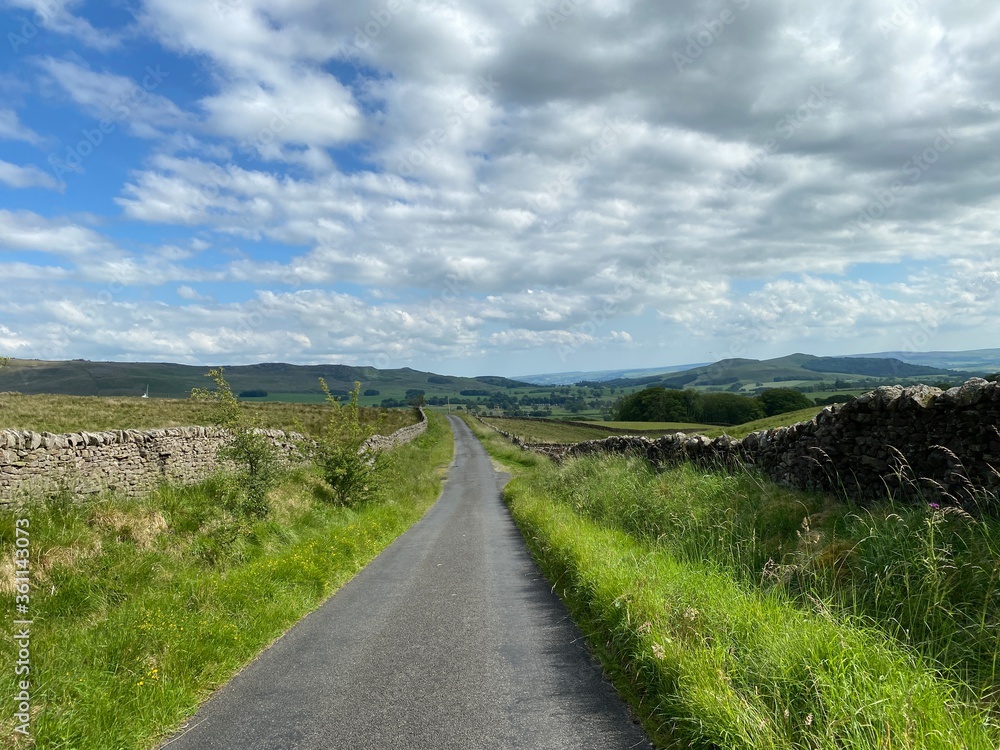 Country road, with grass verges and dry stone walls, in the Yorkshire dales near, Skipton, Yorkshire, UK