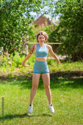 squat, jumping exercises. girl plays sports in garden. fitness after childbirth. © andrey