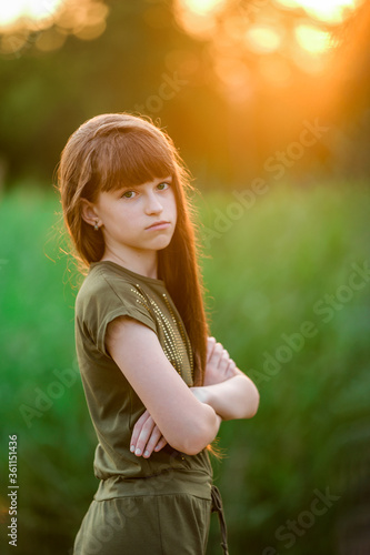 Portrait of a girl with long flowing hair at sunset. Street photography. Green-eyed beautiful girl