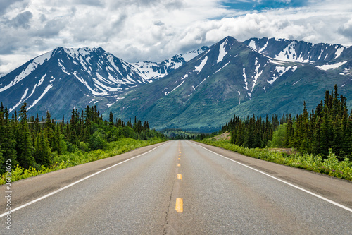 Road winding through the Alaskan wilderness in summer surrounded by mountains photo