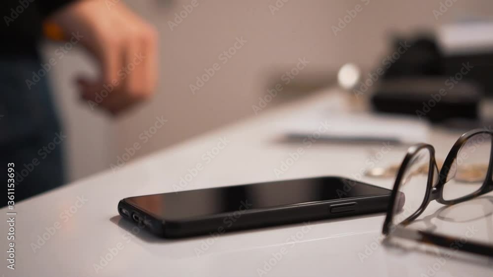 Slow motion shot of a male hand placing a smartphone on a table beside a pair of glasses Slow motion shot of a male hand placing a smartphone on a table beside a pair of glasses