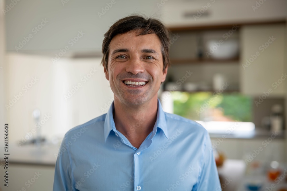Obraz premium Close up of handsome happy man is smiling in camera after having a breakfast in a kitchen at home.
