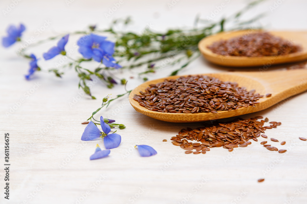 Flax seeds and a blue flower of flax on a wooden background. Healthy food and drink concept. Flax seeds is a superfood