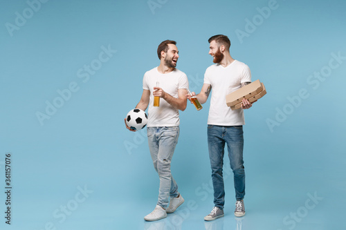 Laughing men guys friends in white t-shirt isolated on blue background. Sport leisure concept. Cheer up support favorite team with ball, beer bottle, pizza in cardboard flatbox, looking at each other.