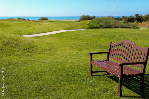 bench on a large green lawn with sea views