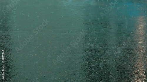 Rain in the city: Raindrops hit the asphalt. Handheld shot. 
Shallow depth of field.